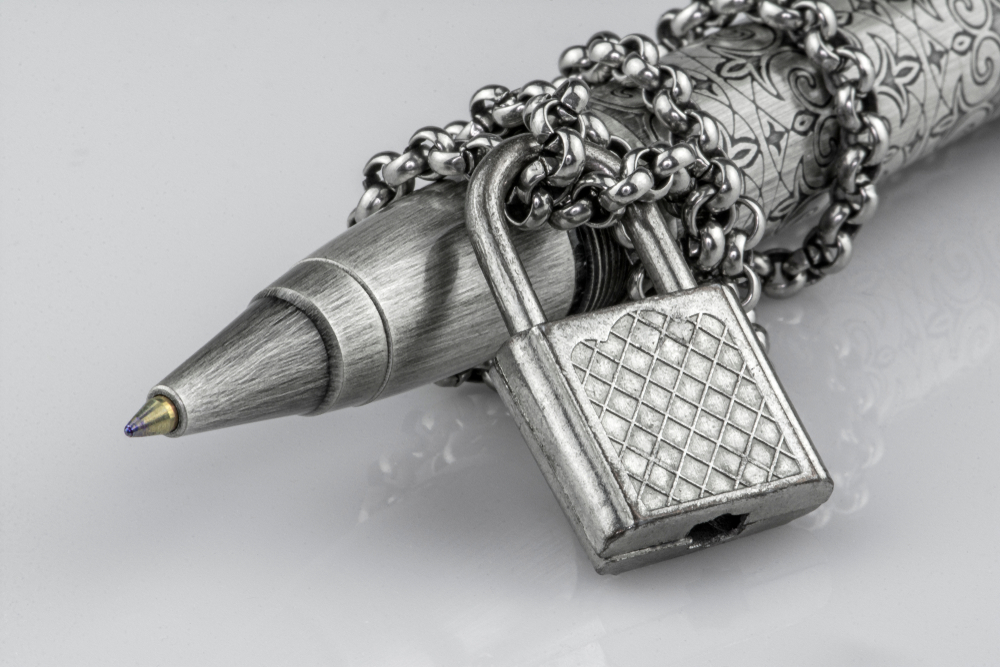 Ball point pen with chain and lock representing free press restriction. 
