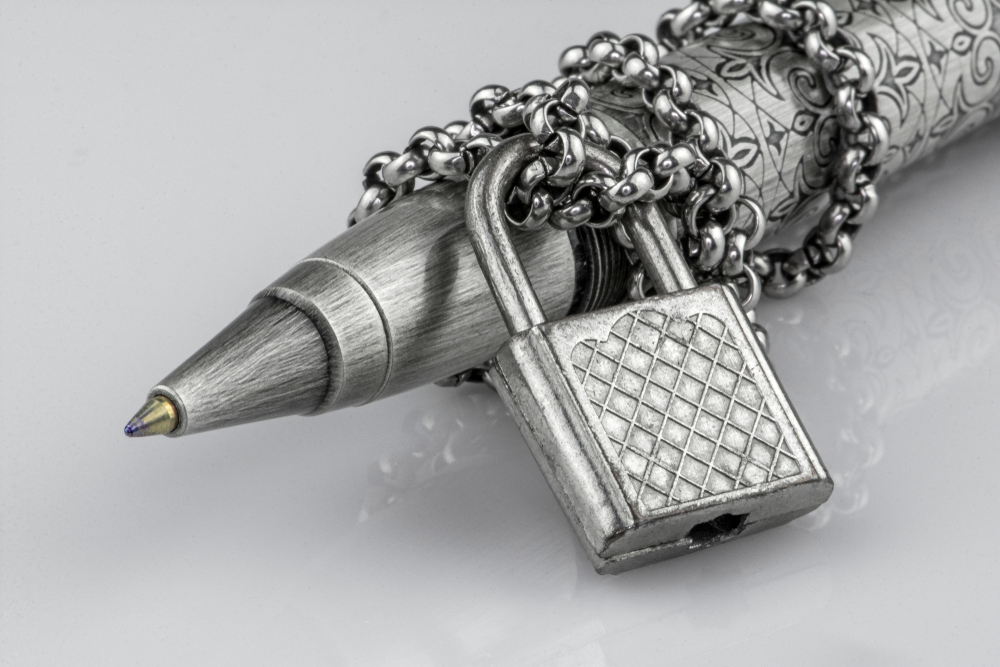 Ball point pen with chain and lock representing free press restriction.
