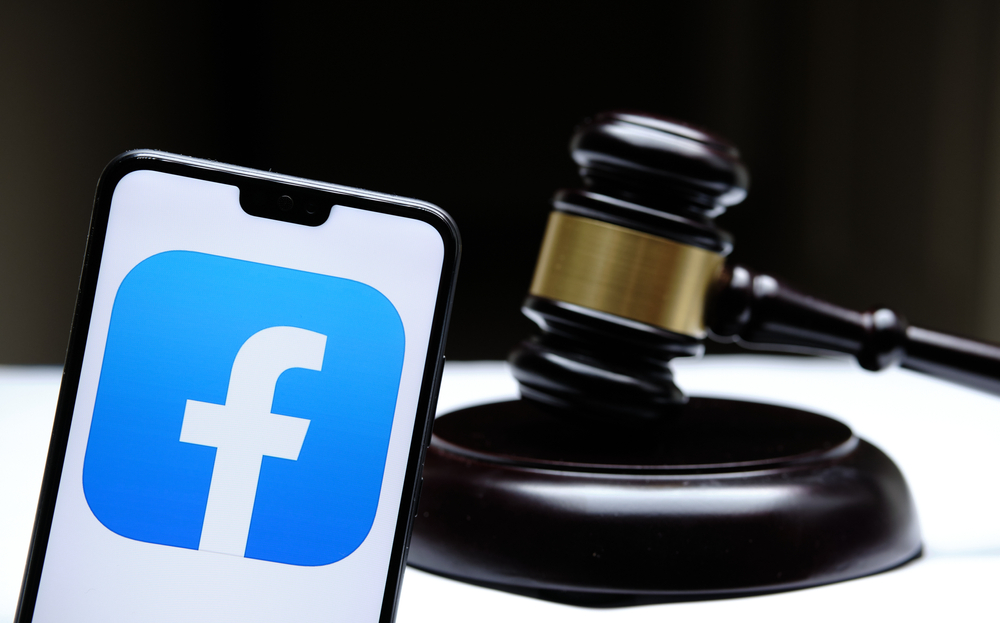 Courtroom gavel next to a Facebook icon on a mobile phone.